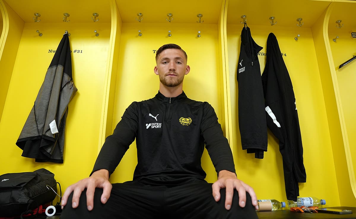 Bild på Noel Törnqvist sittandes i Mjällby AIF:s omklädningsrum.